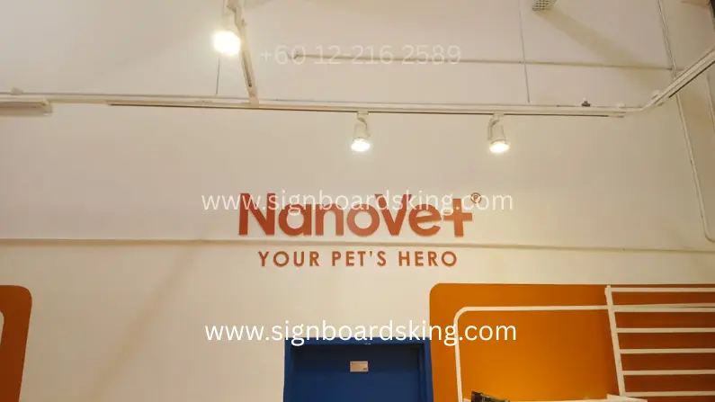 3D PVC Lettering Signage NanoVet dengan huruf timbul oren dipasang pada dinding ruang dalaman.
